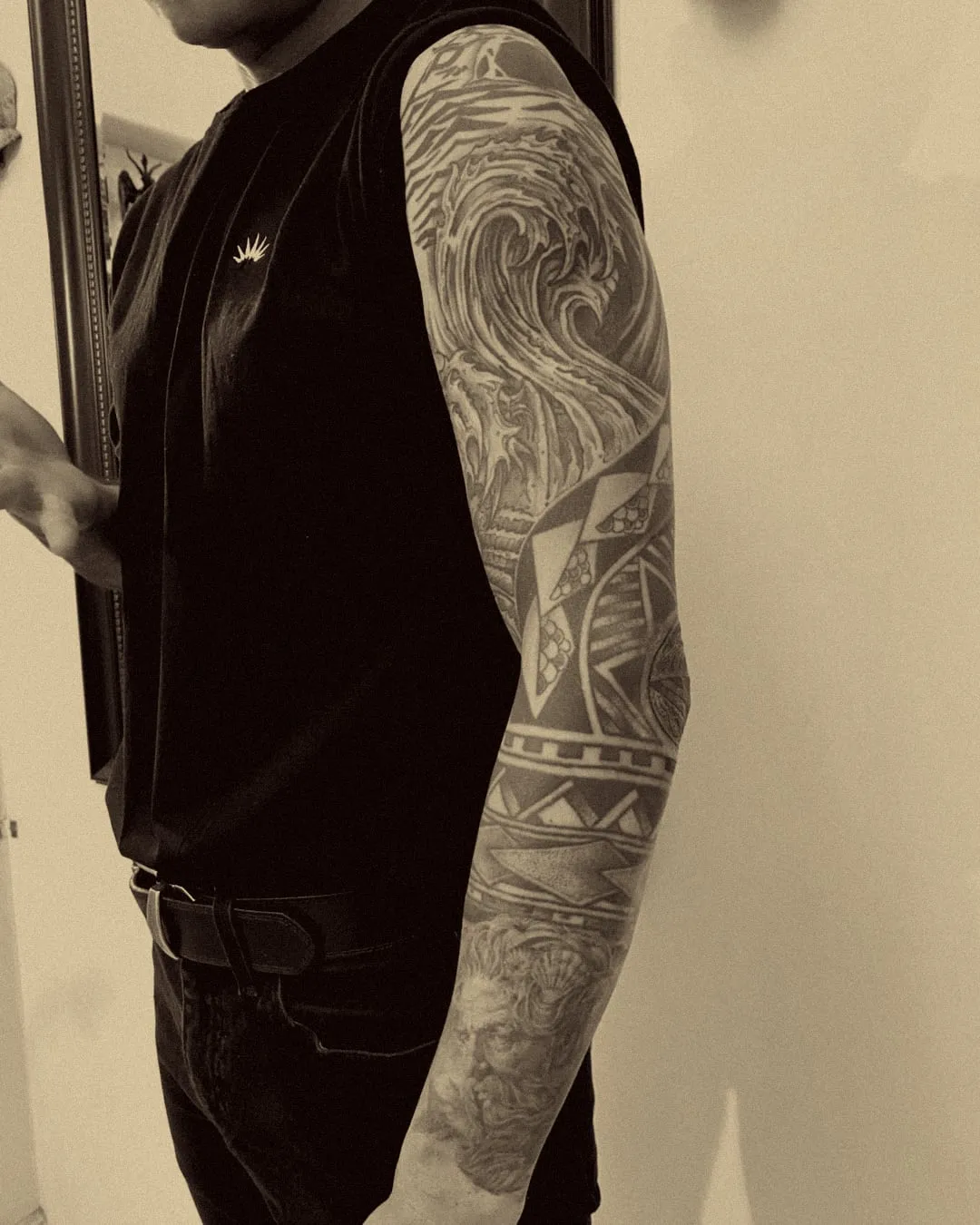 Manga completa con olas y diseño polinesio en negro y gris, restaurada en el brazo